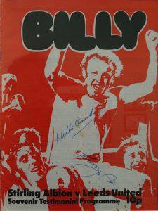 Football match programme with a picture of Billy Bremner on cover and signed by Billy Bremner. The Cover is mostly red and white.