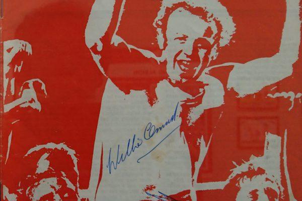 Football match programme with a picture of Billy Bremner on cover and signed by Billy Bremner. The Cover is mostly red and white.